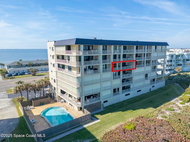 view of building exterior with a water view and a community pool