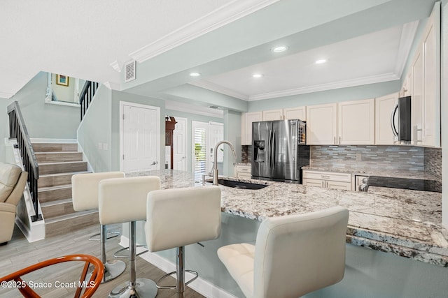 kitchen with tasteful backsplash, sink, a kitchen breakfast bar, light stone counters, and stainless steel appliances