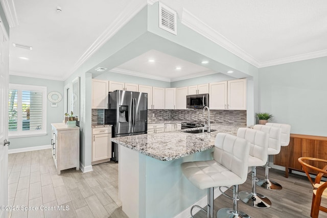 kitchen with a breakfast bar, sink, kitchen peninsula, stainless steel appliances, and light stone countertops