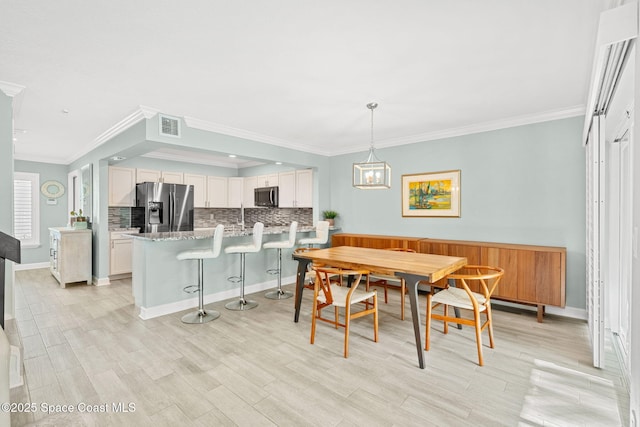 dining room with breakfast area, ornamental molding, light hardwood / wood-style floors, and sink