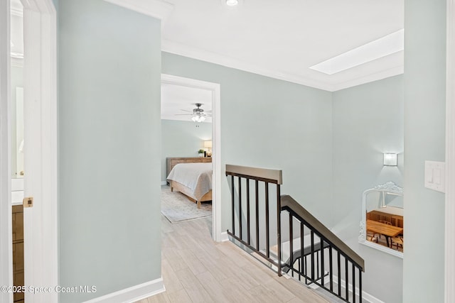 hall with crown molding, a skylight, and light hardwood / wood-style floors