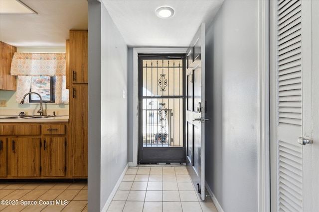 doorway with light tile patterned flooring, baseboards, and a sink