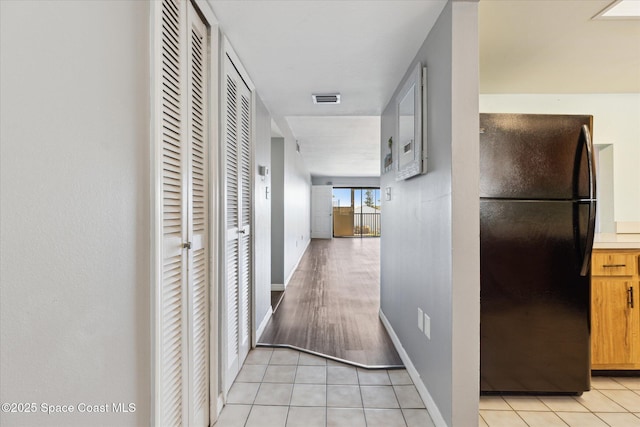 corridor with light tile patterned floors, visible vents, and baseboards