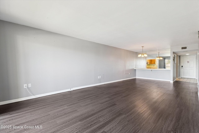 unfurnished living room with dark wood-style floors, baseboards, and a chandelier