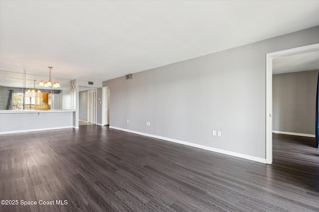 unfurnished living room with a chandelier, baseboards, visible vents, and dark wood finished floors