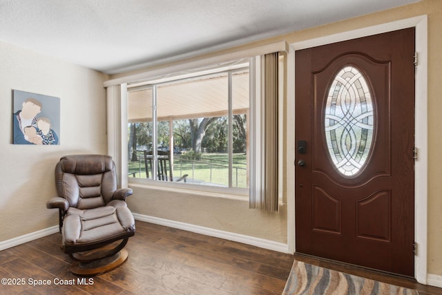 foyer with dark wood-style flooring and baseboards