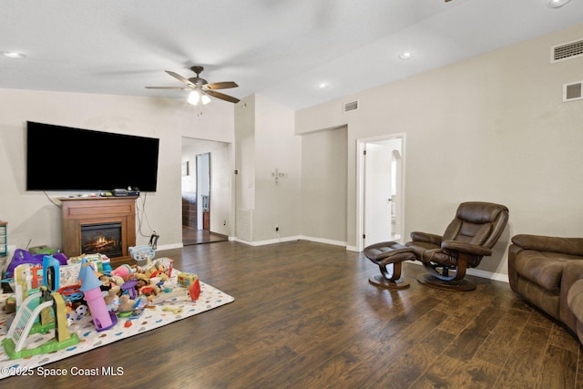 living area with lofted ceiling, dark wood-type flooring, a glass covered fireplace, and visible vents