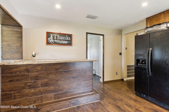 kitchen with light countertops, black fridge, dark wood finished floors, and visible vents