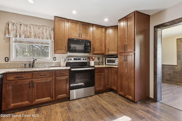 kitchen with black appliances, dark wood-style flooring, a sink, and brown cabinets