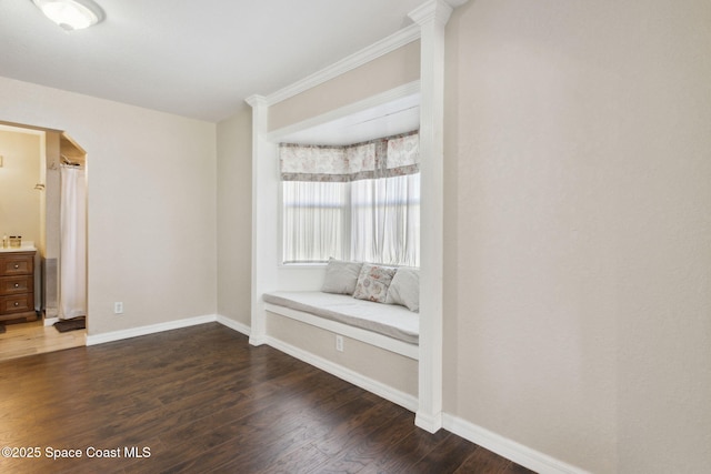 interior space with dark wood-style floors, arched walkways, and baseboards