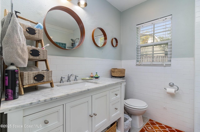 bathroom featuring vanity, tile walls, and toilet