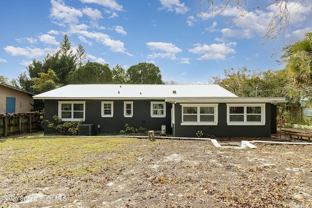 rear view of house featuring cooling unit and a lawn