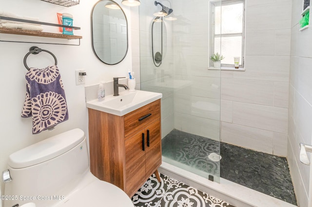 bathroom featuring a tile shower, vanity, and toilet