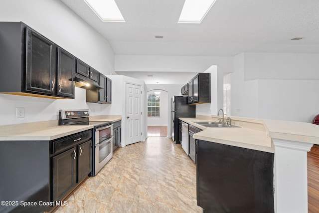 kitchen featuring black fridge, double oven range, kitchen peninsula, and sink