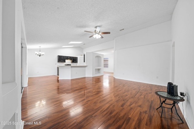 unfurnished living room featuring dark hardwood / wood-style flooring, vaulted ceiling, ceiling fan with notable chandelier, and a textured ceiling