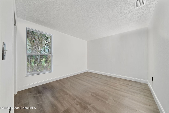 spare room featuring light hardwood / wood-style floors and a textured ceiling