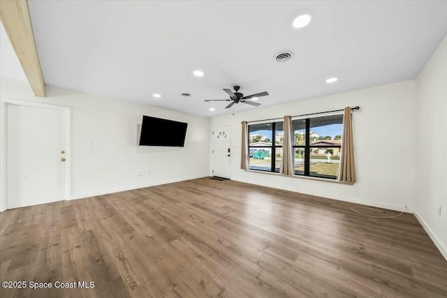 unfurnished living room featuring ceiling fan, beam ceiling, and hardwood / wood-style floors