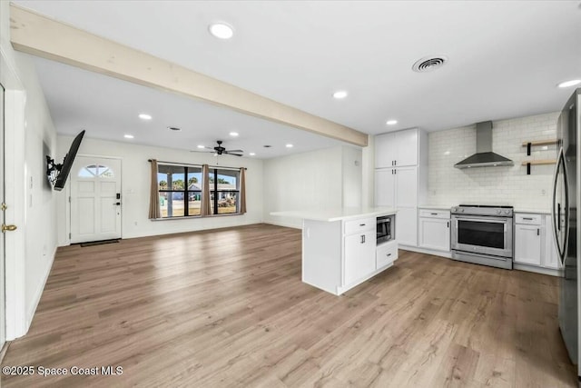 kitchen featuring light hardwood / wood-style flooring, white cabinetry, stainless steel appliances, decorative backsplash, and wall chimney exhaust hood