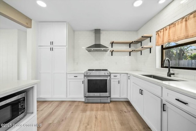 kitchen with sink, white cabinetry, backsplash, stainless steel appliances, and wall chimney exhaust hood