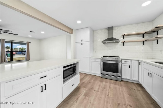 kitchen featuring wall chimney exhaust hood, white cabinets, stainless steel appliances, light hardwood / wood-style floors, and backsplash