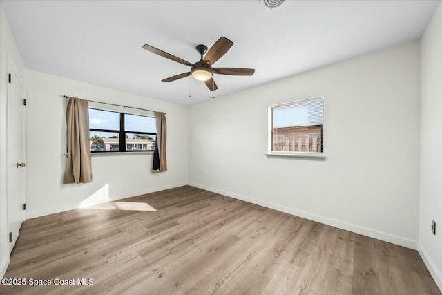 empty room with ceiling fan, plenty of natural light, and light hardwood / wood-style floors