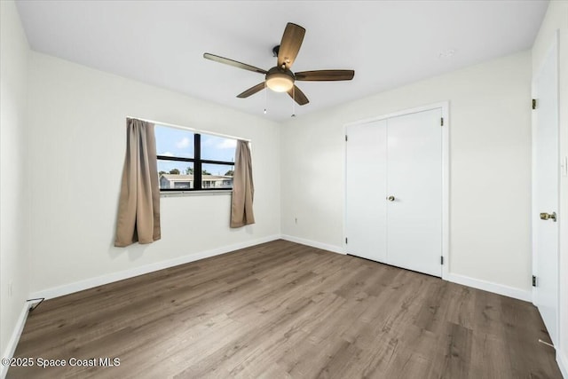 unfurnished bedroom featuring hardwood / wood-style floors, a closet, and ceiling fan