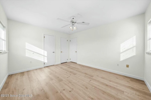 unfurnished bedroom with two closets, light hardwood / wood-style floors, and ceiling fan