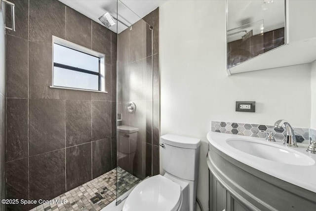 bathroom featuring vanity, a tile shower, and toilet