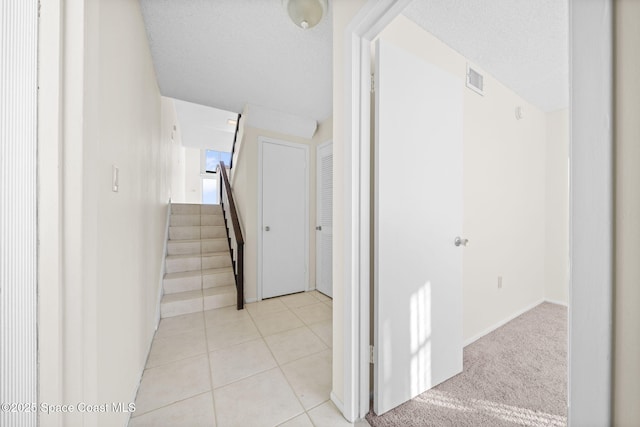 staircase featuring tile patterned floors and a textured ceiling