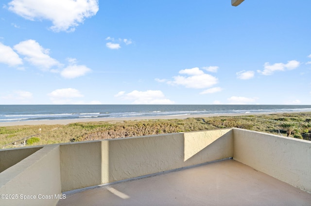 balcony with a water view and a view of the beach