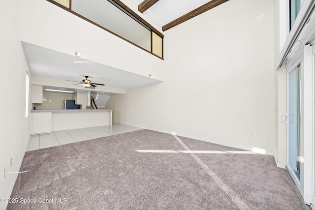 unfurnished living room with beamed ceiling, ceiling fan, light carpet, and high vaulted ceiling