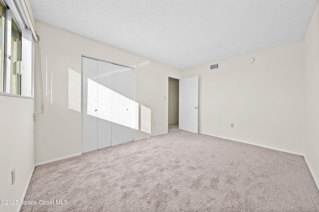 empty room with light carpet and a textured ceiling