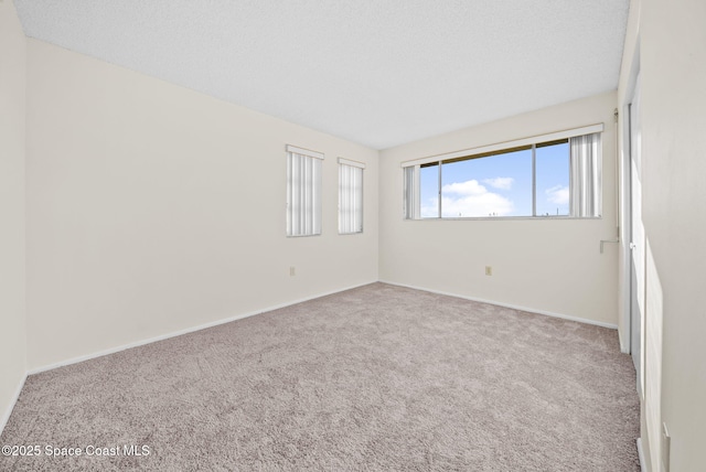 empty room with light colored carpet and a textured ceiling