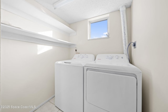 clothes washing area featuring washing machine and dryer, light tile patterned floors, and a textured ceiling