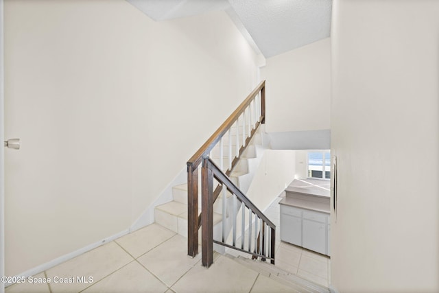 stairway featuring tile patterned floors and a textured ceiling