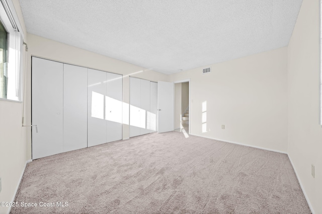 unfurnished bedroom featuring light carpet and a textured ceiling