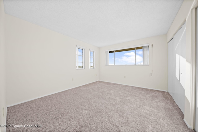 carpeted empty room featuring a wealth of natural light and a textured ceiling