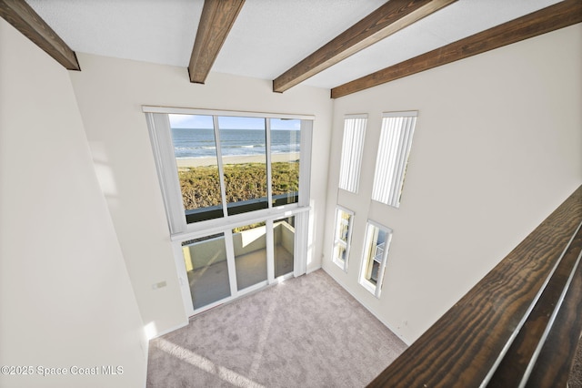 unfurnished living room with light colored carpet and beam ceiling