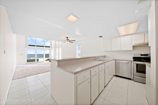 kitchen with white cabinetry, stainless steel appliances, kitchen peninsula, and light carpet