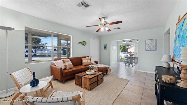 living room featuring light tile patterned floors, a textured ceiling, and ceiling fan