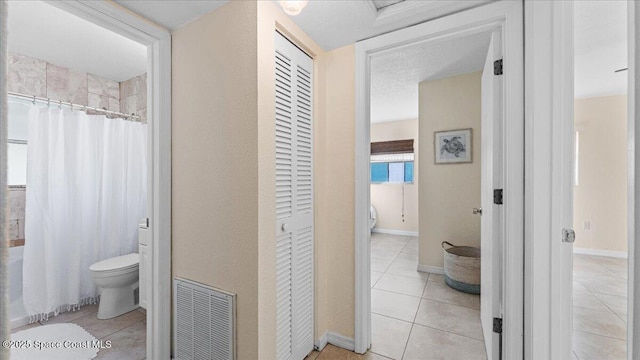 bathroom featuring a shower with curtain, tile patterned floors, and toilet