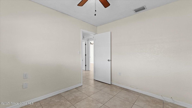 tiled spare room with ceiling fan