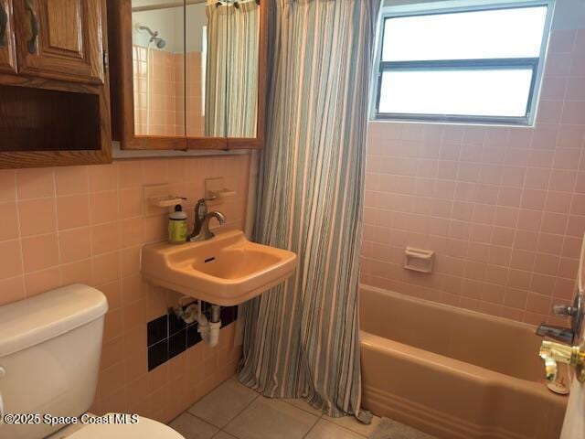 full bath featuring tile walls, shower / bath combo with shower curtain, toilet, and tile patterned flooring