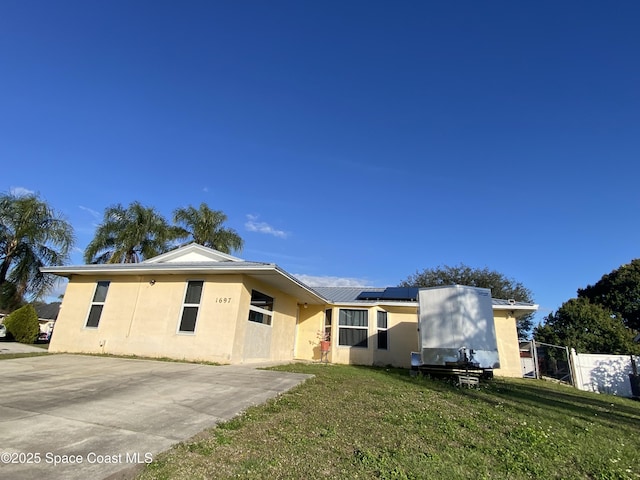 view of front of home with a front lawn and solar panels