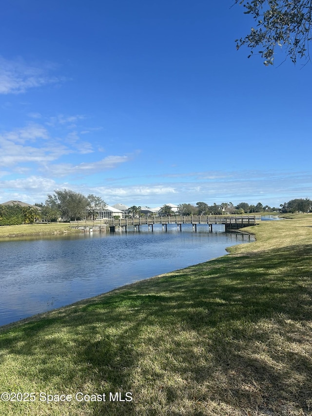 view of dock with a lawn and a water view