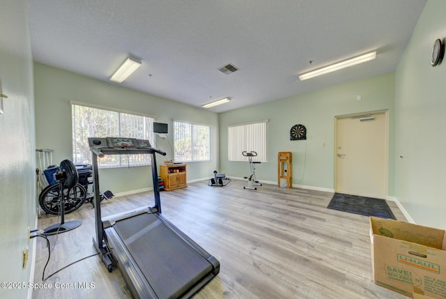 workout area with a textured ceiling and light hardwood / wood-style flooring