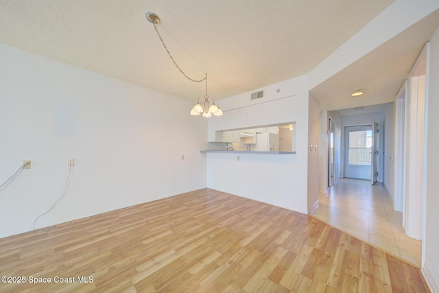 interior space featuring a chandelier, a textured ceiling, and light hardwood / wood-style floors