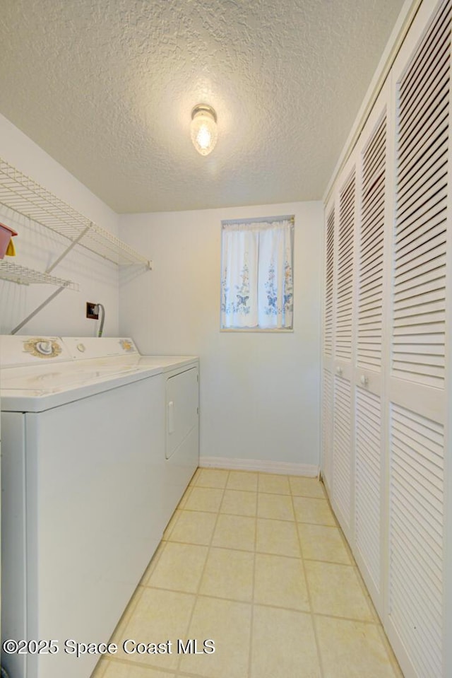 clothes washing area with light tile patterned floors, a textured ceiling, and independent washer and dryer