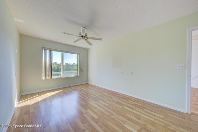 spare room with ceiling fan, light hardwood / wood-style flooring, and a textured ceiling