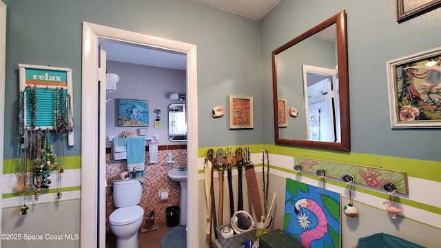 bathroom featuring tile walls, a textured ceiling, and toilet